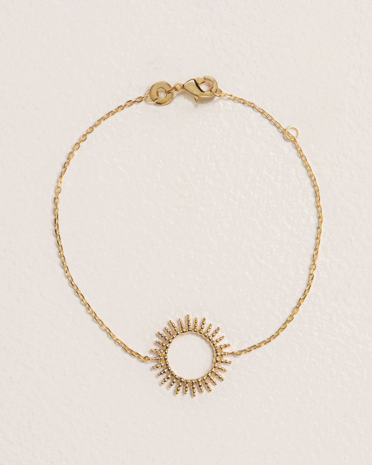 A 18k gold-plated bracelet featuring a sun-shaped centerpiece.