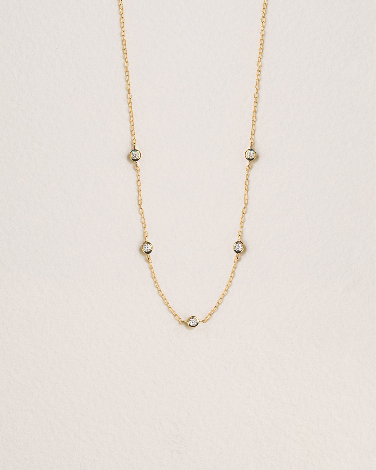 A 18k gold-plated necklace featuring a chain design with delicate zirconia eyes at various points along a chain.