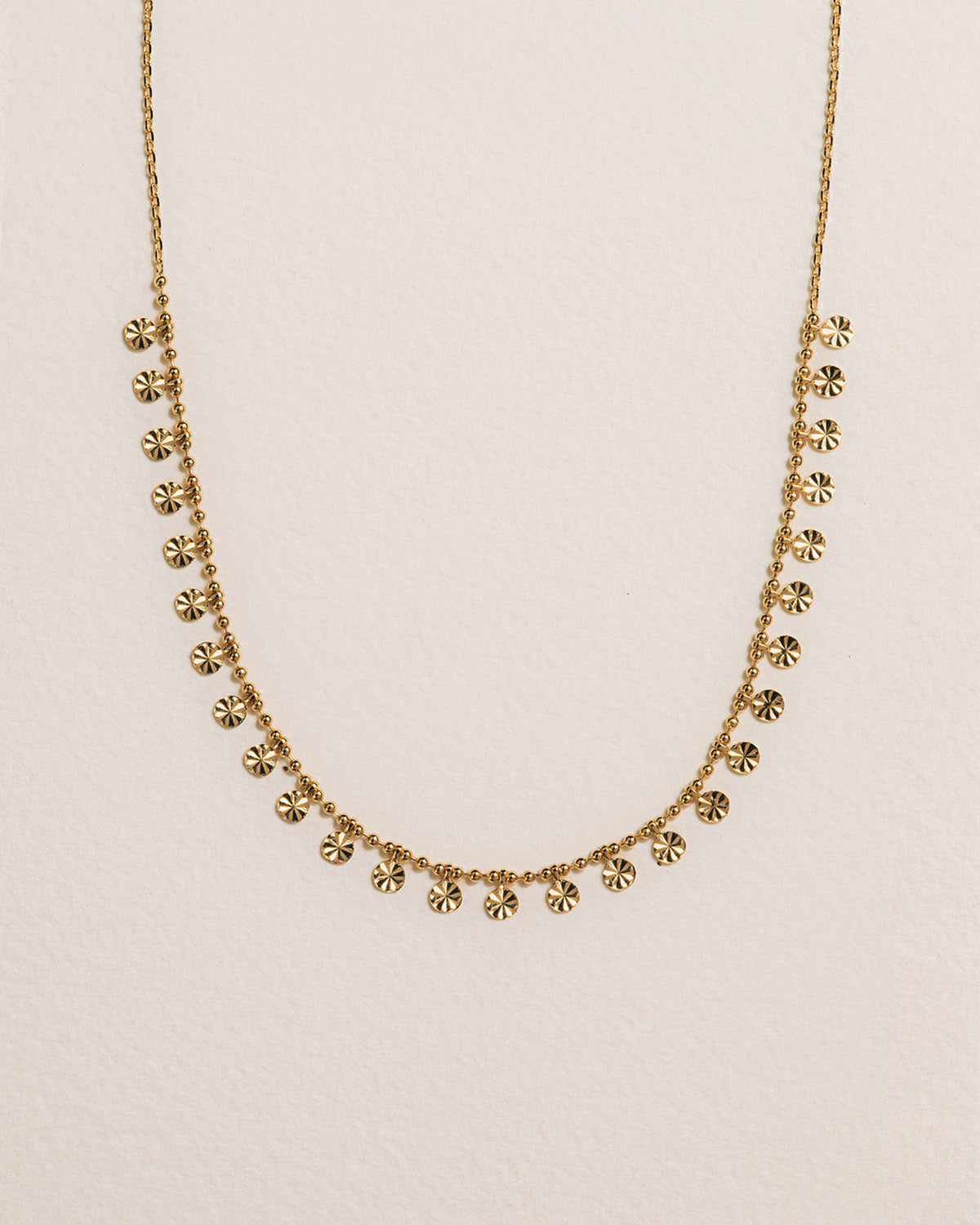 A 18k gold-plated colored necklace with a chain link design and small, regular golden drops evenly spaced along the length.
