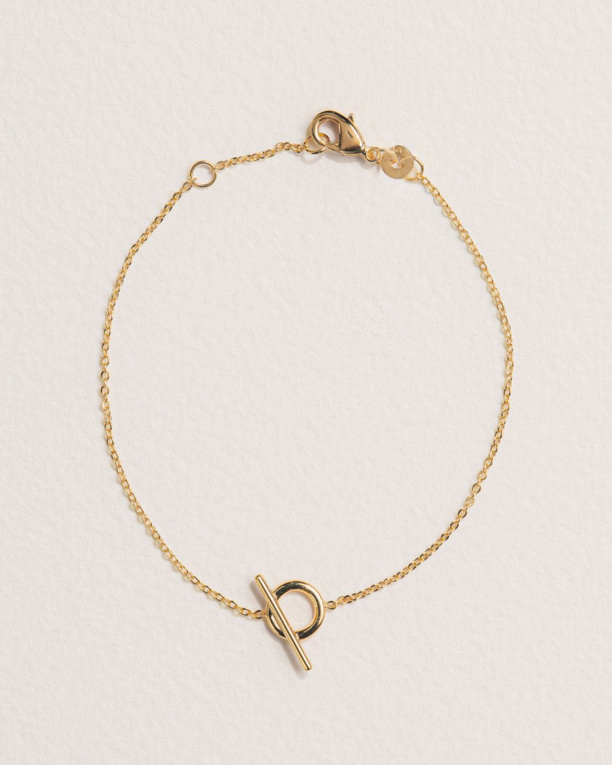 A 18k gold-plated bracelet with a polished sphere and a T-clasp fastening.
