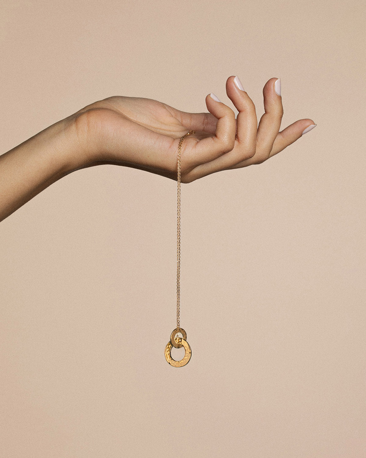 A 18k gold-plated hammered necklace held on a hand