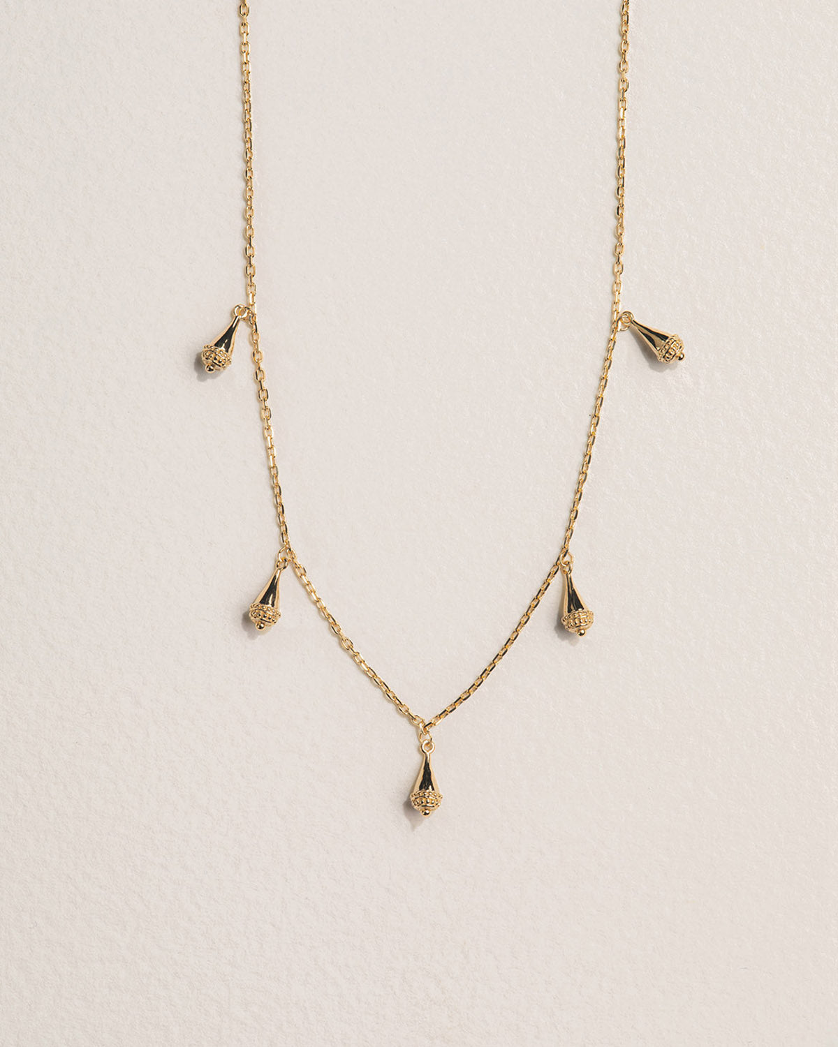 A 18k gold-plated necklace with drop-shaped pendants along the chain.