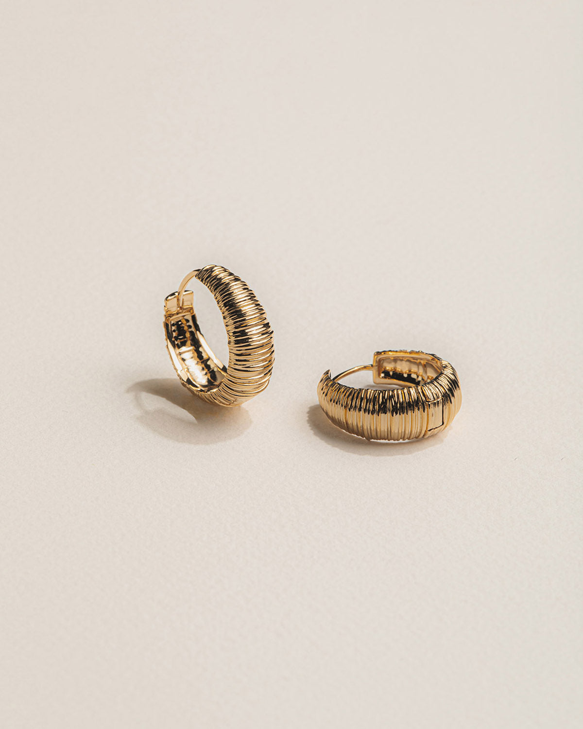A 18k gold-plated pair of hoop earrings with striped patternsbackground.