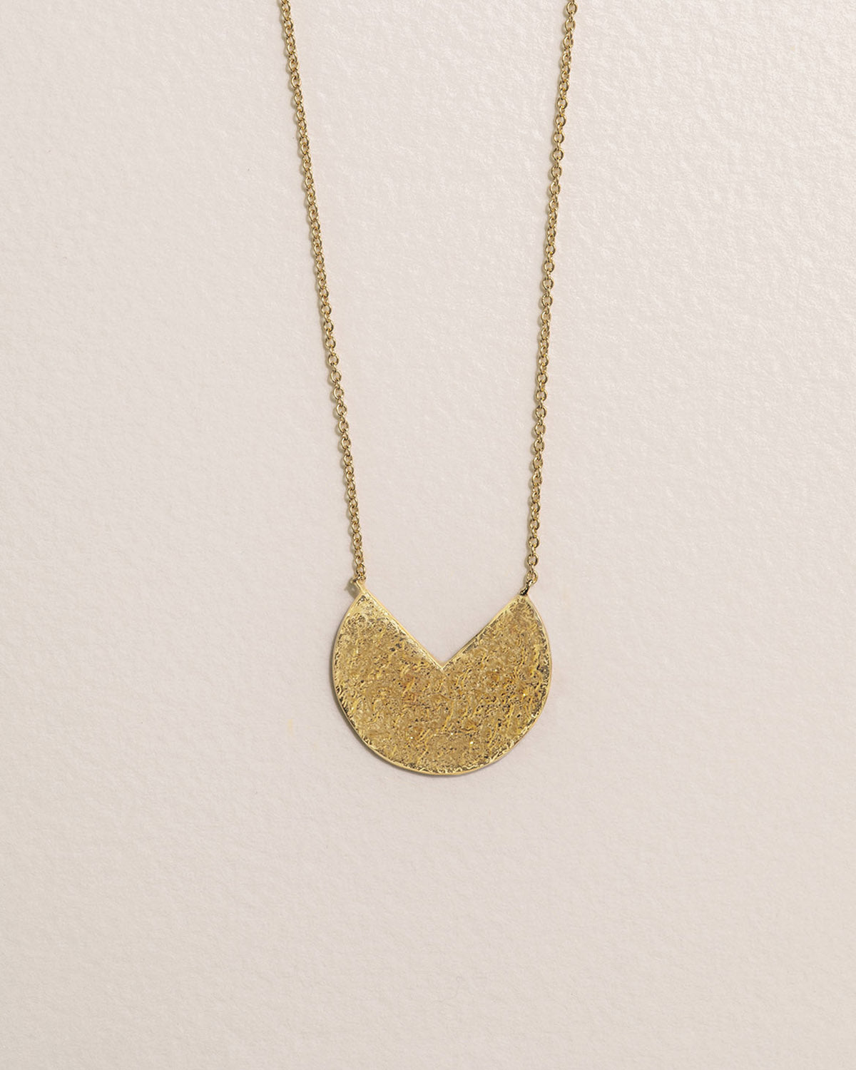 A 18k gold-plated half-moon necklace with a delicately hammered texture.