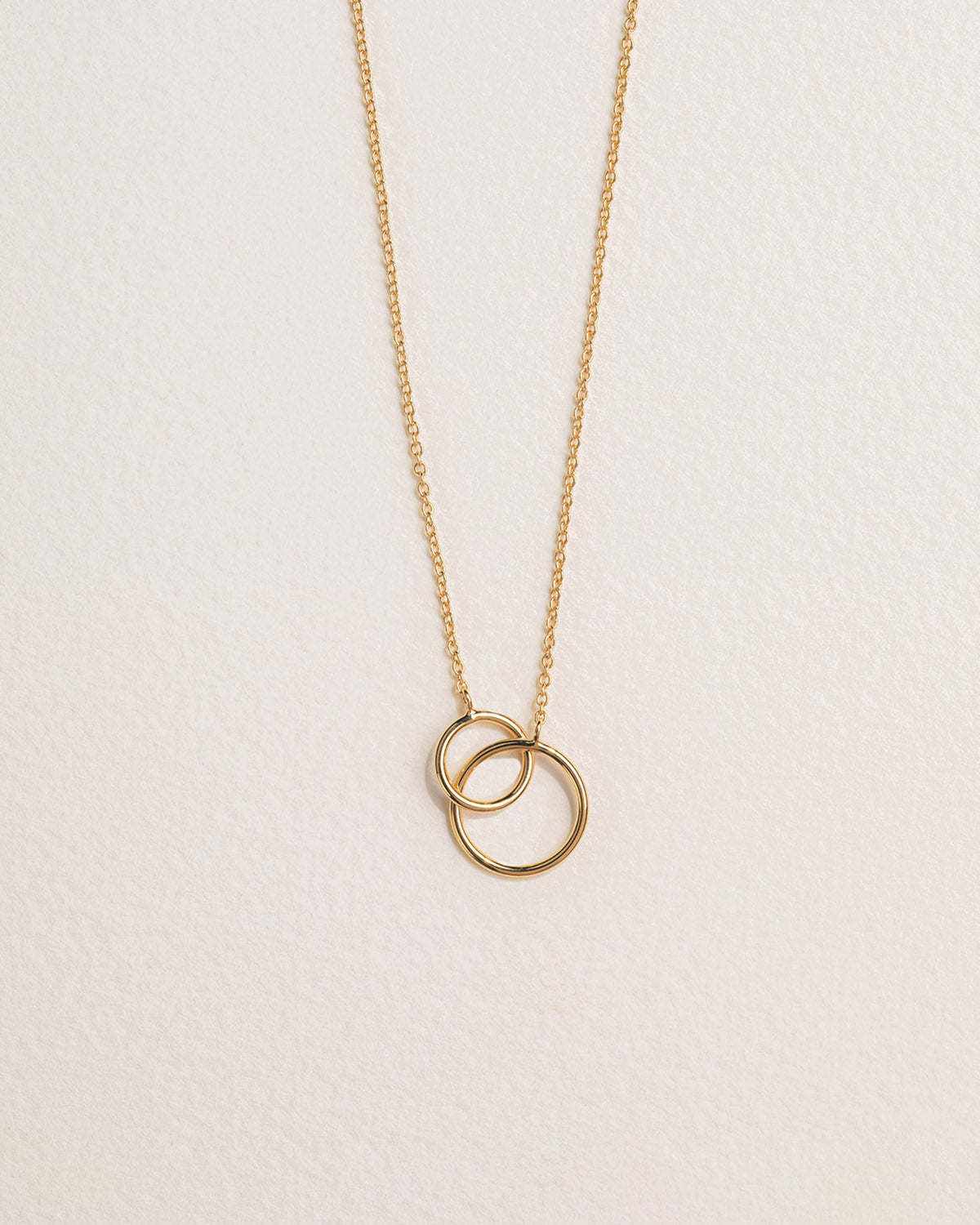 A 18k gold-plated necklace featuring two interlinked rings on a chain.