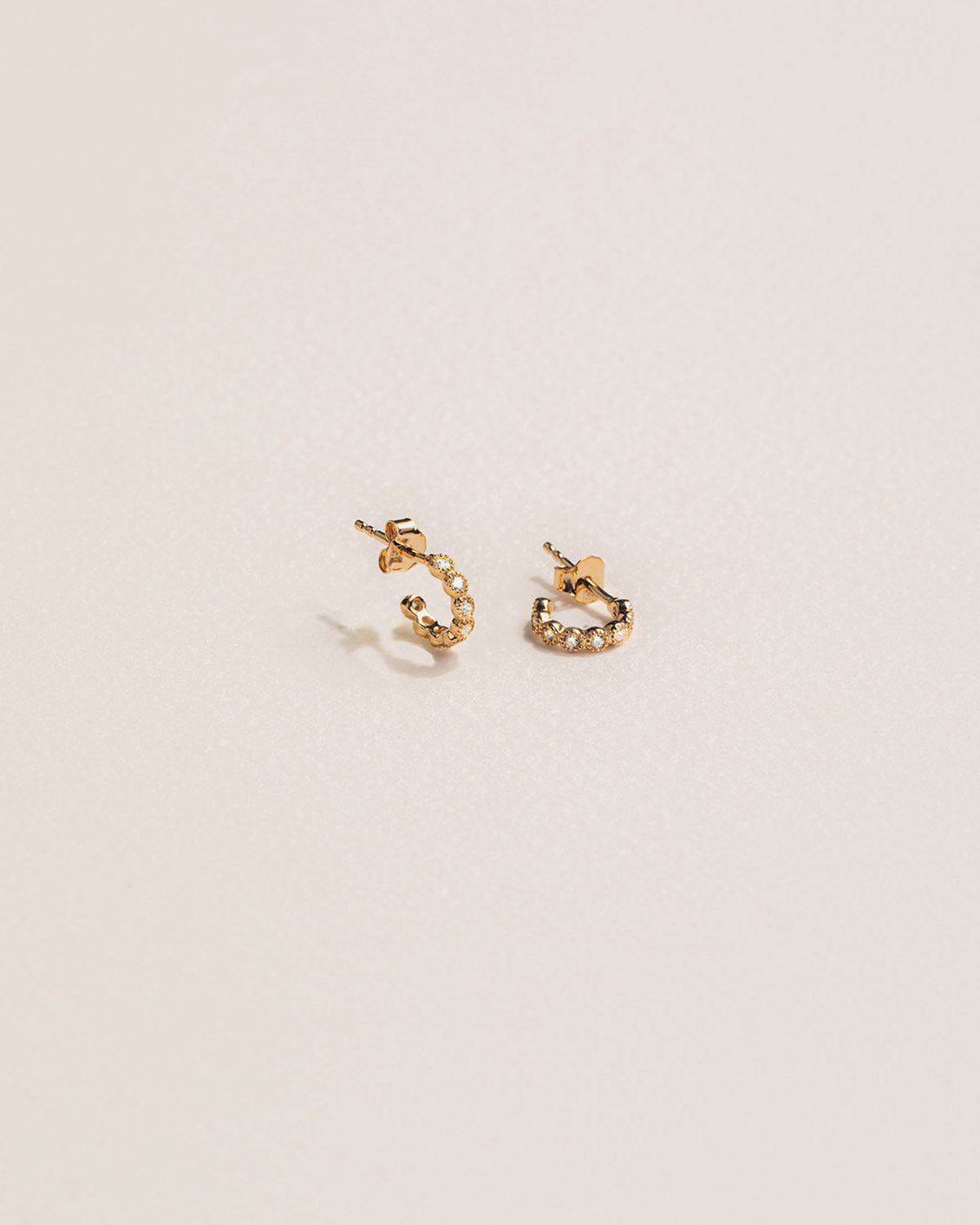 A 18k gold-plated pair of earrings with zirconia-set half-circle crystals aligned on the top part.