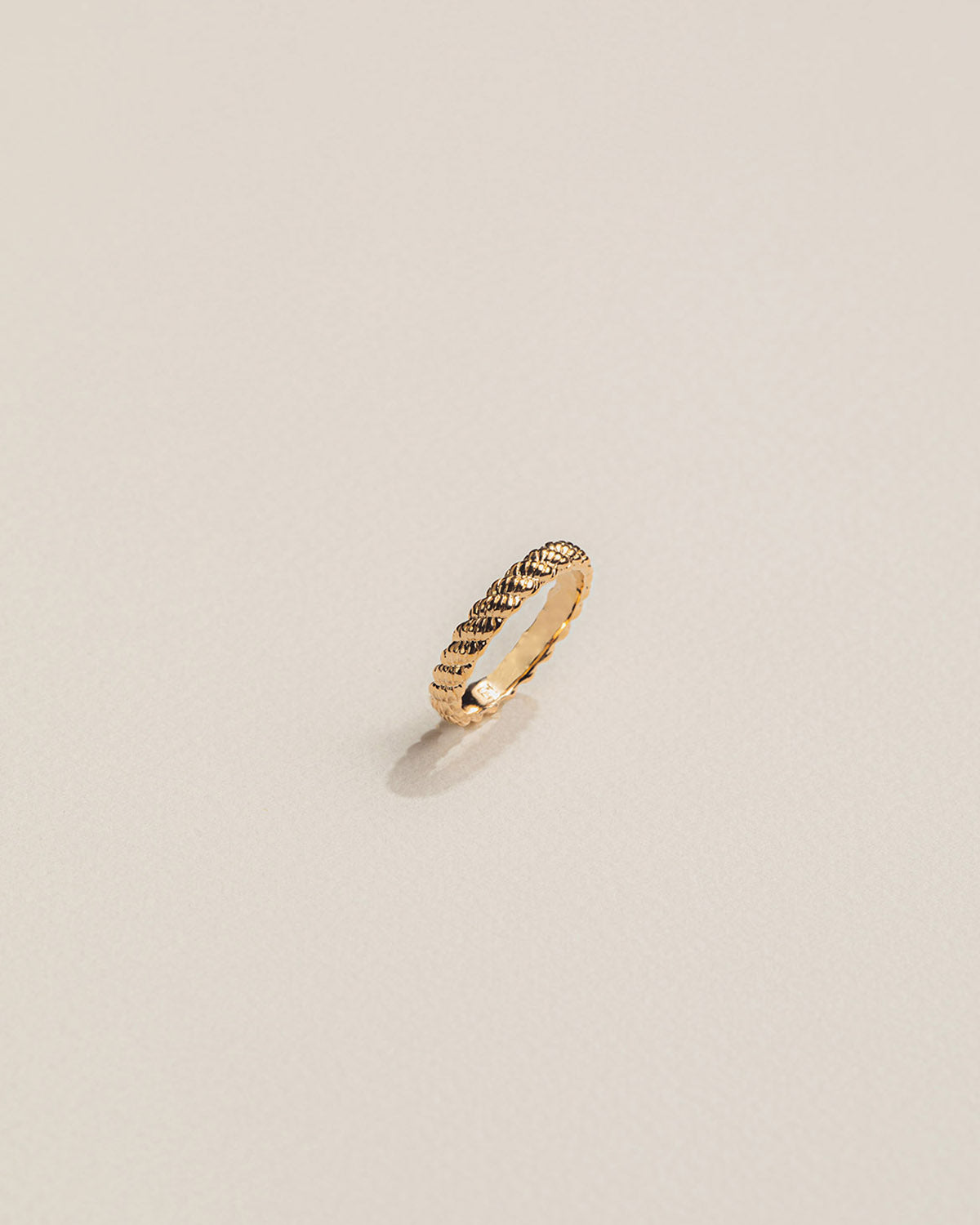 A twisted 18k gold-plated ring with sculpted lines creating a braided effect