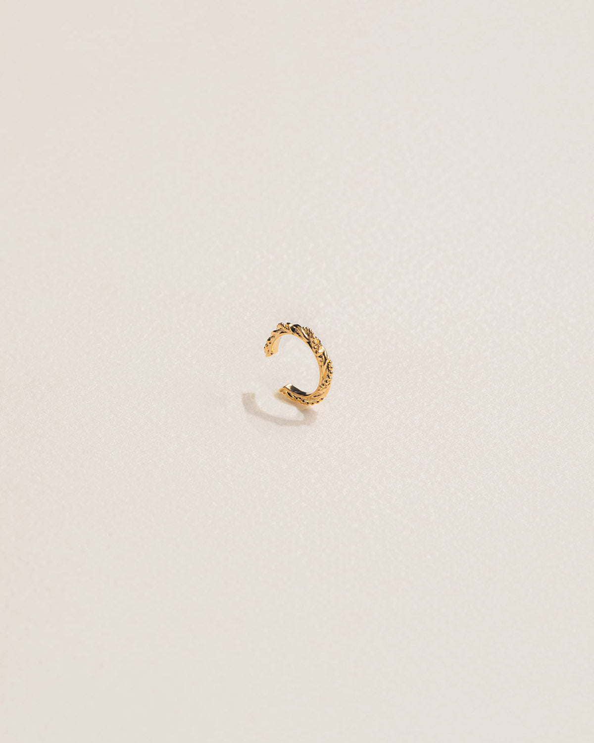 A single 18k gold-plated colored ear cuff featuring a twisted design with golden pearls