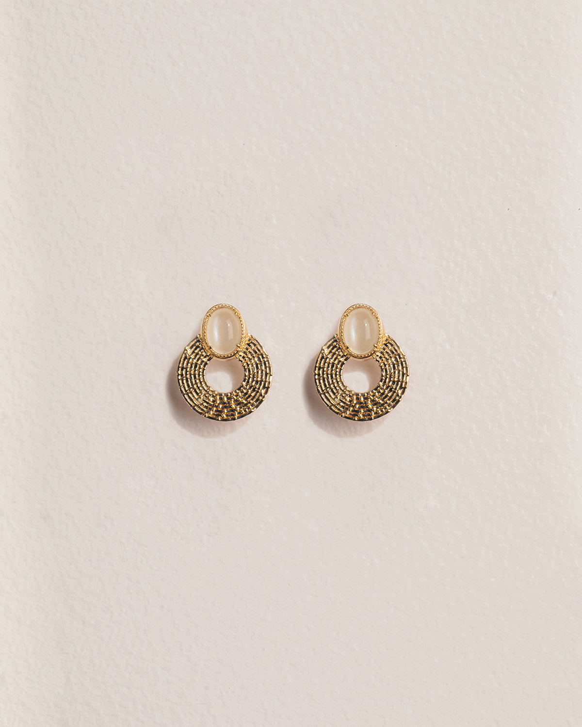 A 18k gold-plated pair of hoop earrings with a textured design and pearly stones on the hoops