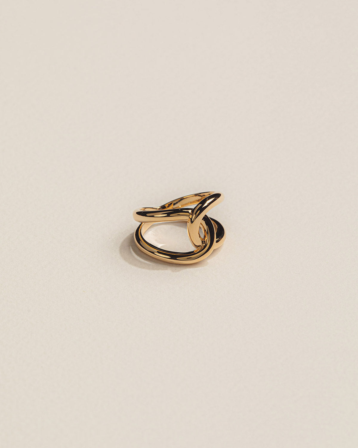 A 18k gold-plated ring with a sculptural design, featuring intertwined bands that resemble the graceful curves of a constellation.