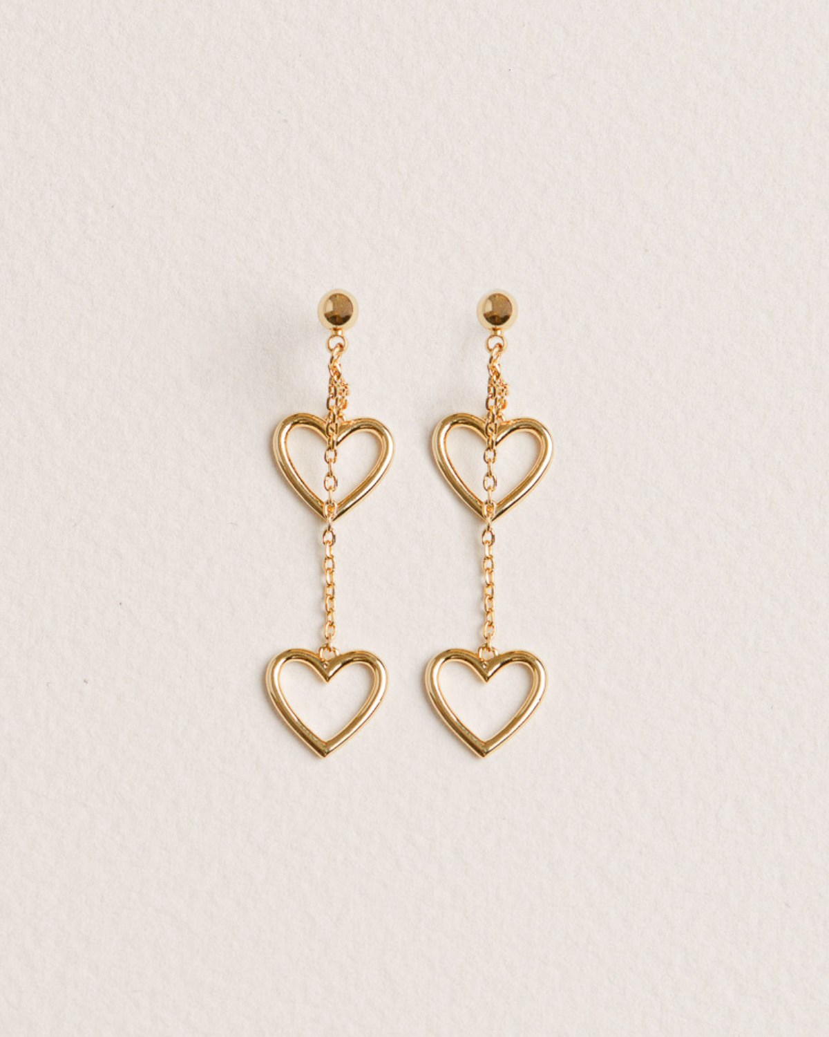 A pair of 18K Gold-plated earrings in the shape of two hearts suspended from a fine chain