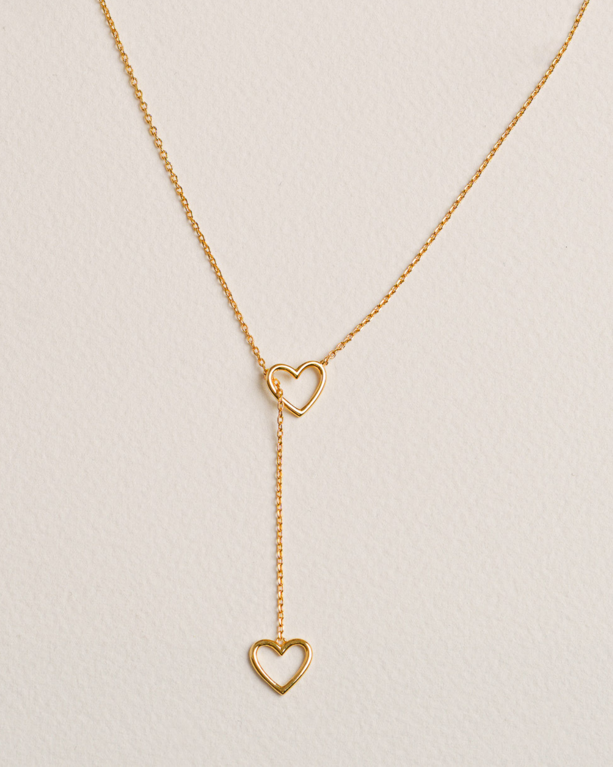 A 18k gold-plated necklace with two intertwined hearts connected by a delicate gold-plated chain
