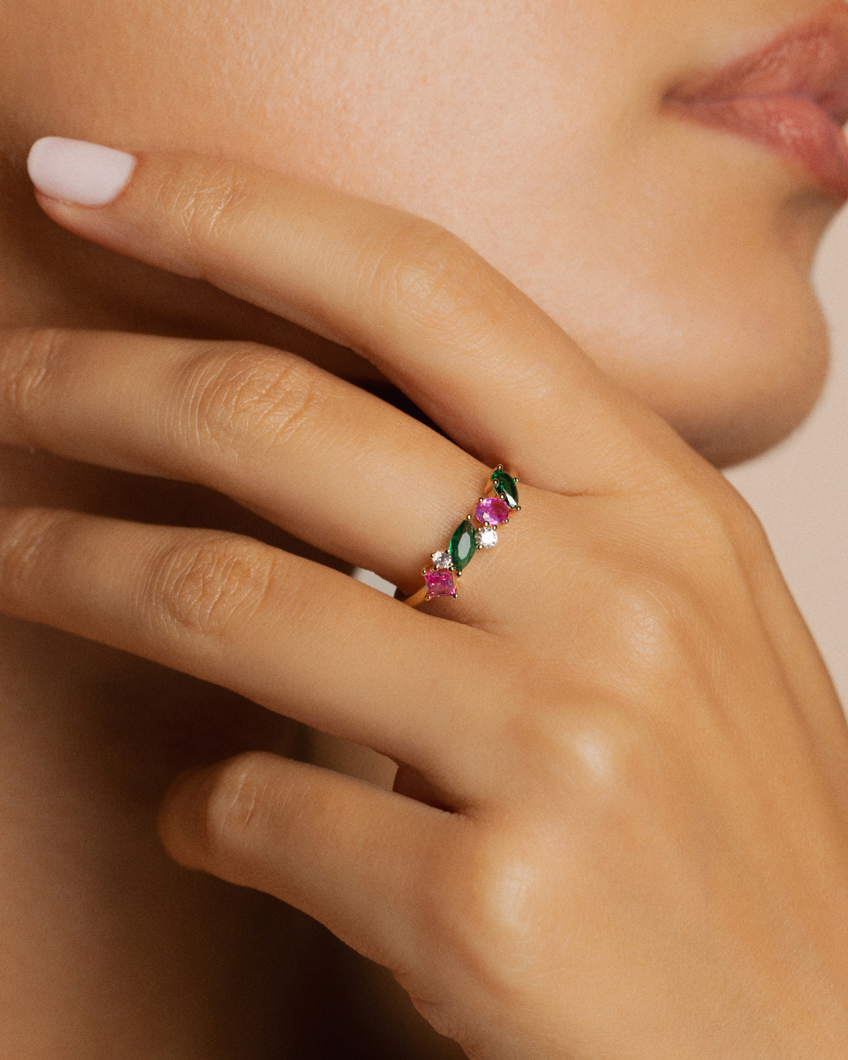 Close-up of a hand wearing a ring with colorful gemstones.