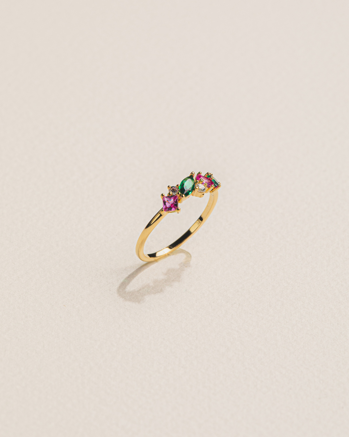18k gold-plated ring with multicolored gemstones on a beige background