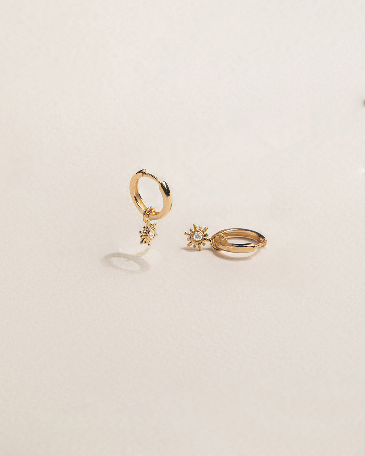 A pair of 18k gold-plated hoop earrings adorned with small sun-like designs