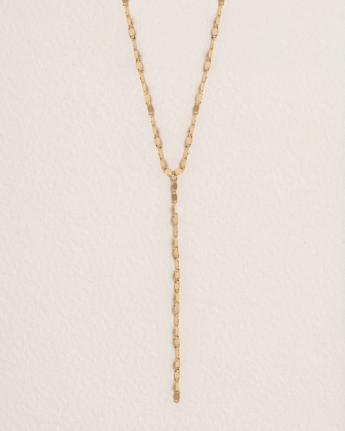 A 18k gold-plated necklace with a minimalist design, featuring a fine chain and a delicate vertical pendant.