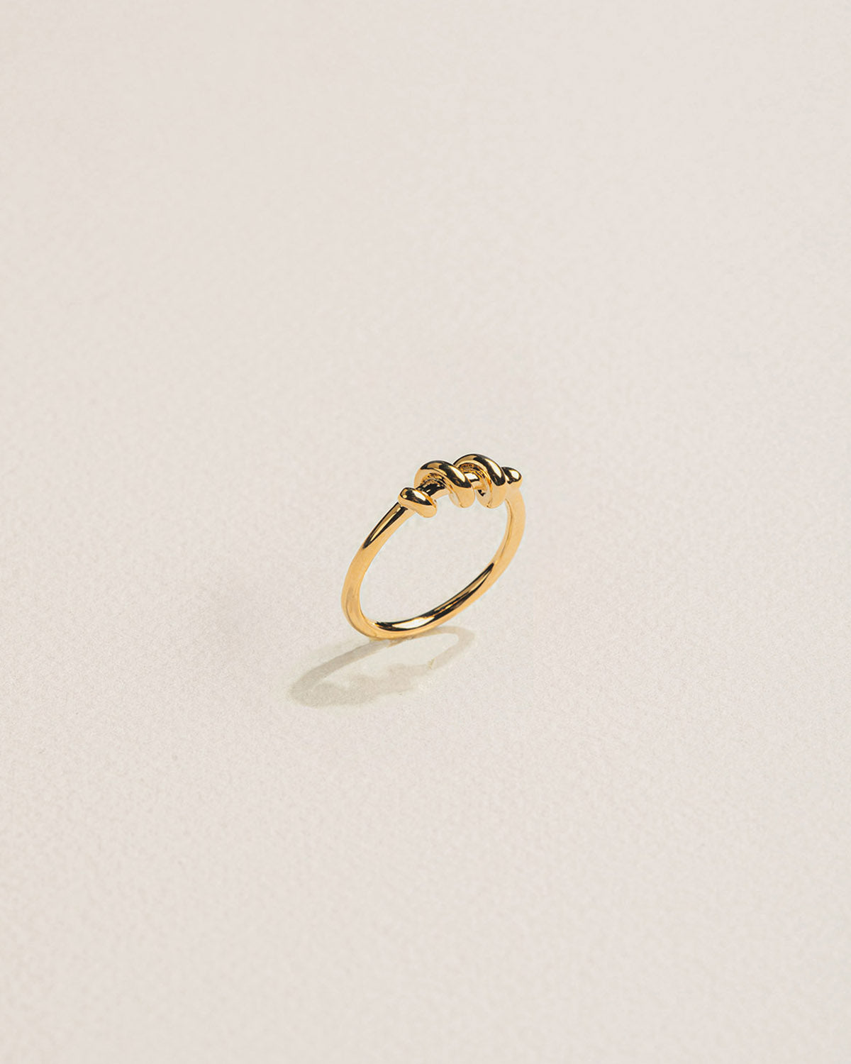 A 18k gold-plated ring intertwined by a thread