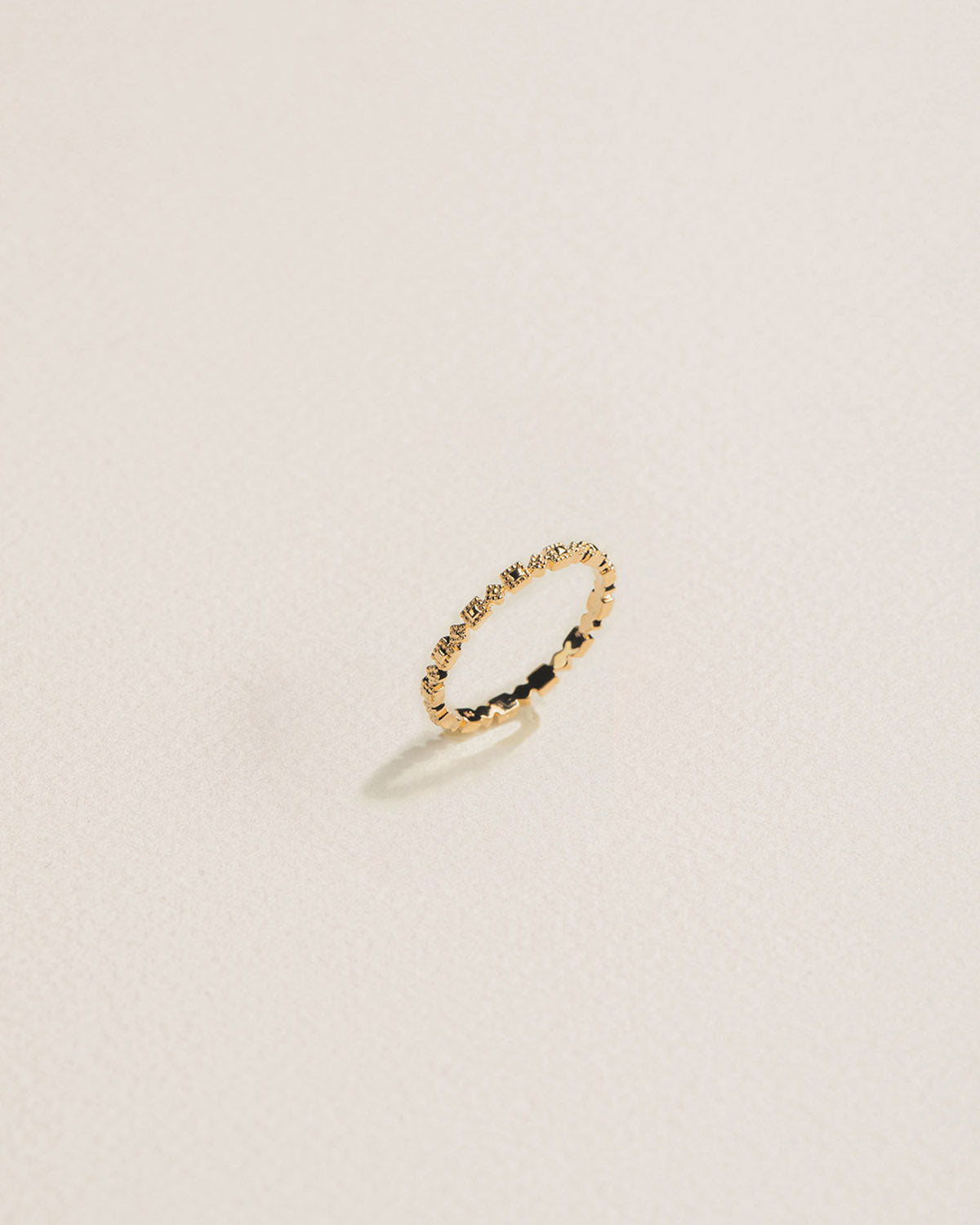 A 18k gold-plated hoop earring with patterns accents on a light background.